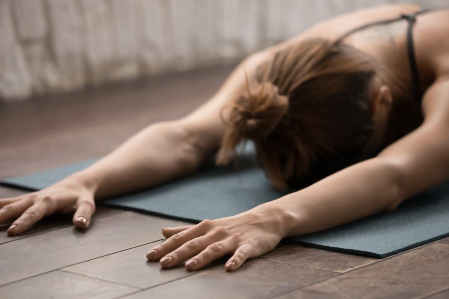 Attractive woman practicing yoga, relaxing after training, lying face down