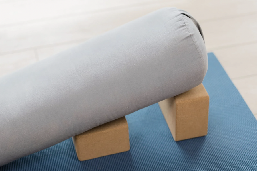 Yoga bolster resting on two blocks on top of a yoga mat