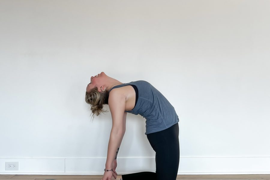 Human in Camel Pose on a green yoga mat