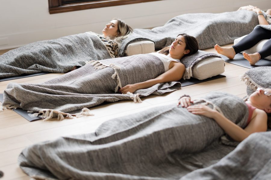 Students lying down with blankets covering them in a Yoga Nidra class