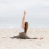 Kate Lombardo surrending to the divine in the sand on a NJ beach with her arms up overhead bringing her palms together.