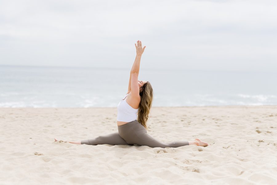 Kate Lombardo surrending to the divine in the sand on a NJ beach with her arms up overhead bringing her palms together.