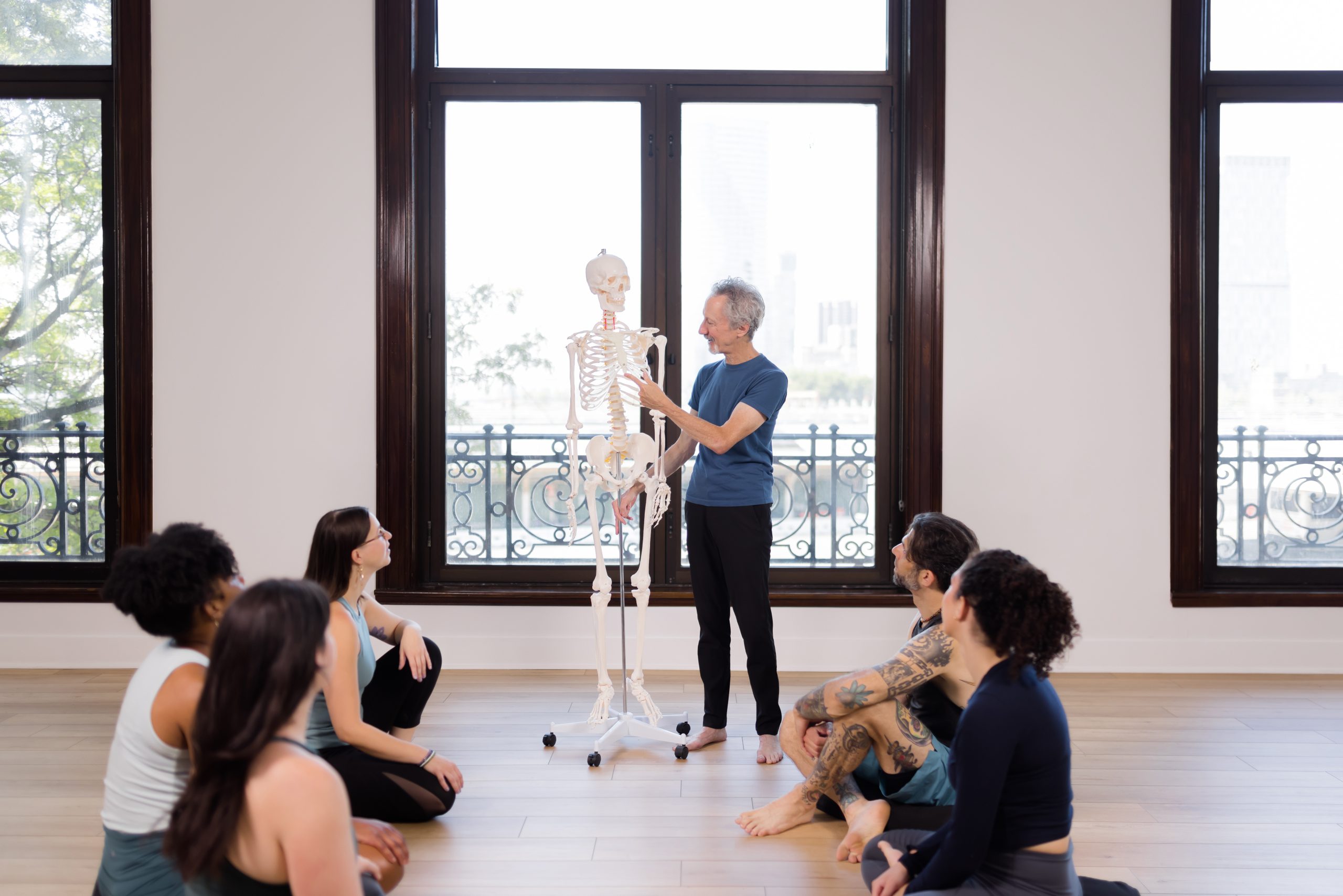 Joe Miller demonstrating on a skeleton in front of 5 yogis for the Bodily Systems & Yoga Workshop