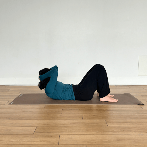 "Articulation of the spine" movement with a person lying on their back, hands behind their head, lifting their head and neck in the direction of their knees