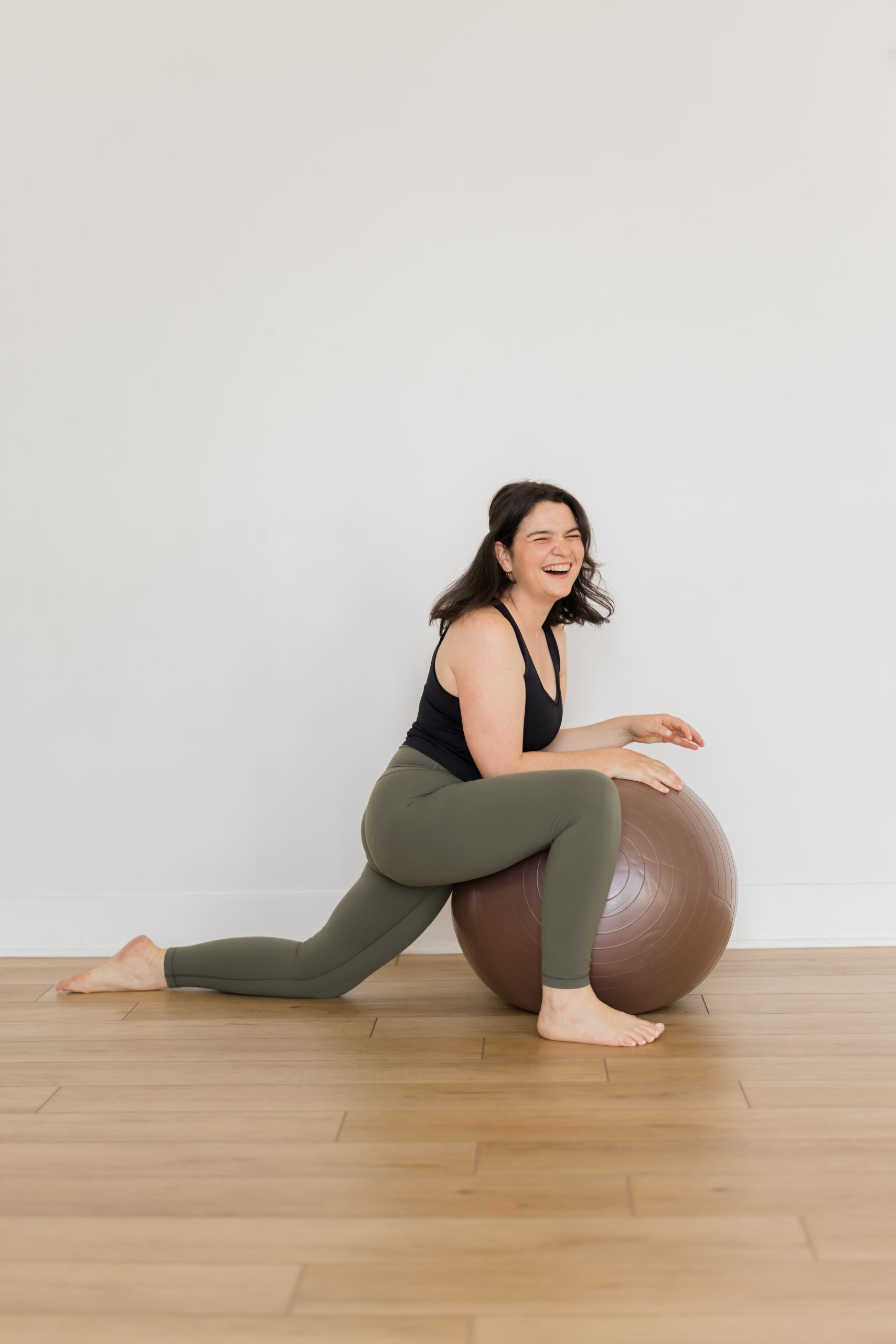 Mélie Purdon, YogaRenew's Prenatal Director, with a pregnancy ball, smiling at the camera in a low lunge