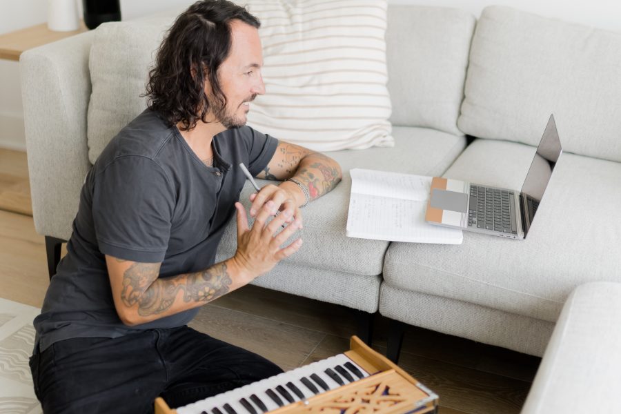 New Year's yoga flow image of Patrick Franco with a harmonium writing out his yoga sequence, looking at a laptop