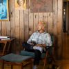 Patrick Franco sitting in a cozy chair, looking down on his reflections from the year in a wood cabin with cool art hanging behind him