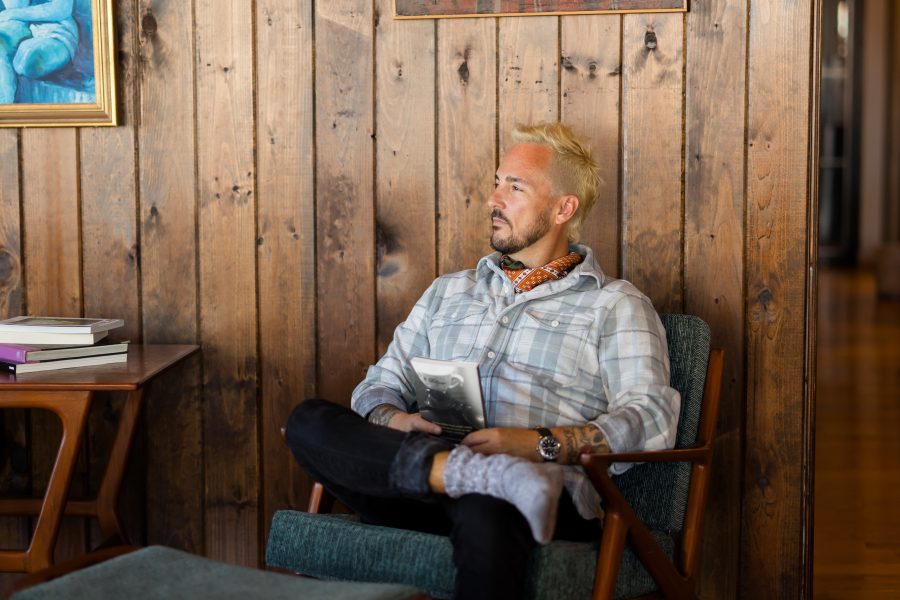 Patrick Franco sitting in a cozy chair, looking down on his reflections from the year in a wood cabin with cool art hanging behind him