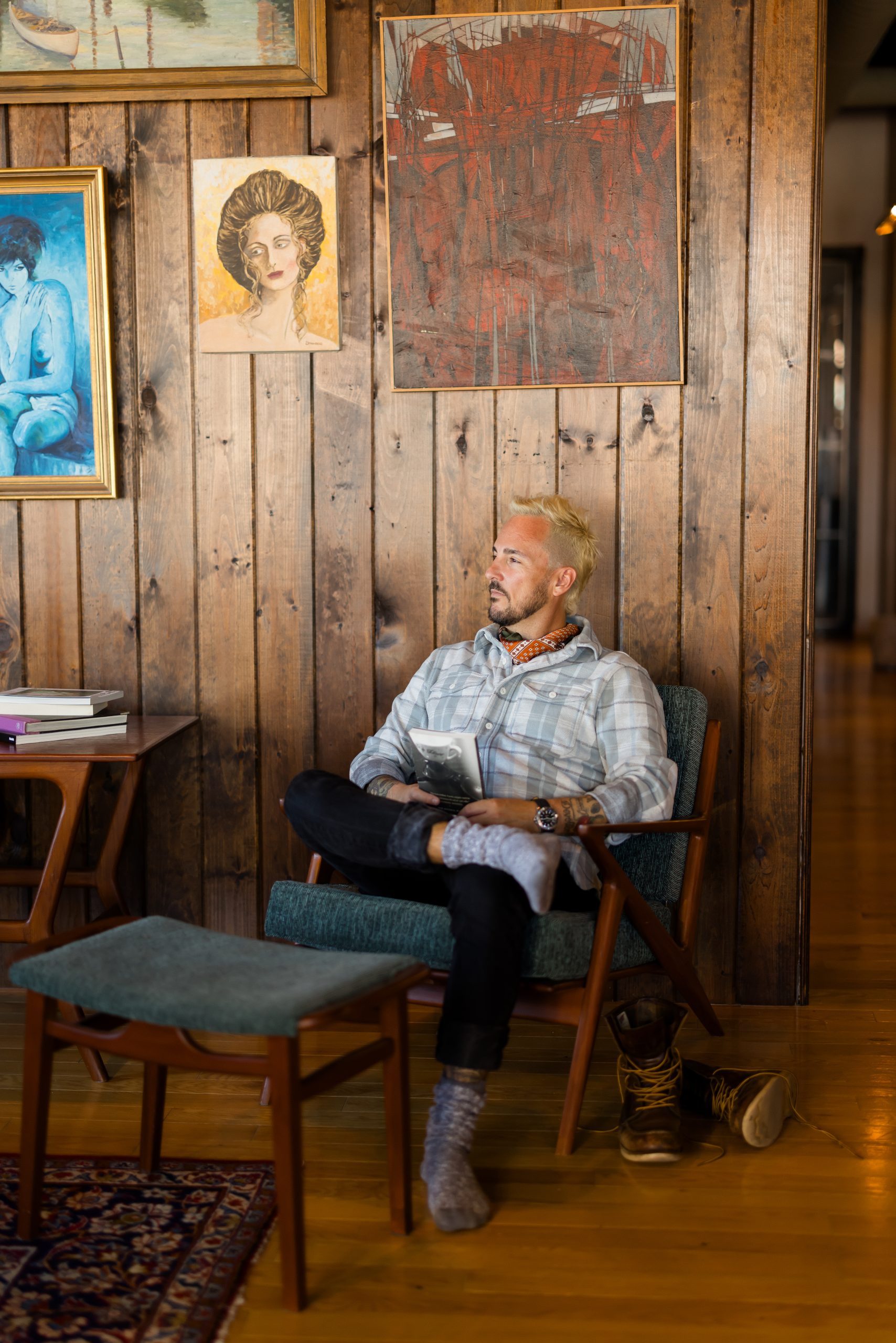 Patrick Franco sitting in a cozy chair, looking down on his reflections from the year in a wood cabin with cool art hanging behind him