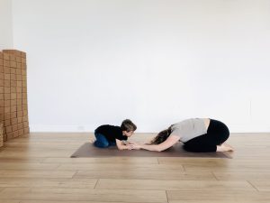 Mother and son facing each other in balasana, child's pose