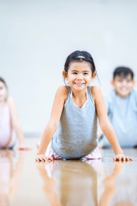 A young kid in cobra pose, smiling at the camera head on