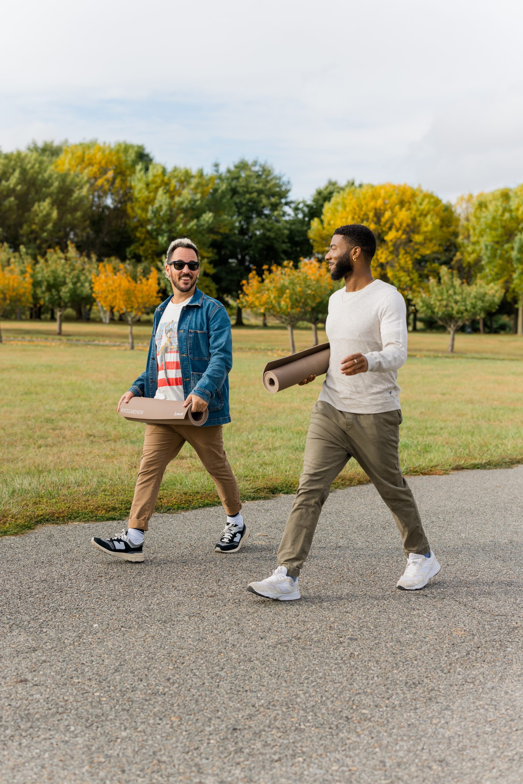 A photo of Patrick Franco and Jordan taking a mindful walk, carrying their rolled up yoga mats