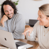 Patrick Franco and Kate Lombardo of YogaRenew looking at a laptop with YogaRenew's 200 hour online yoga teacher training pulled up