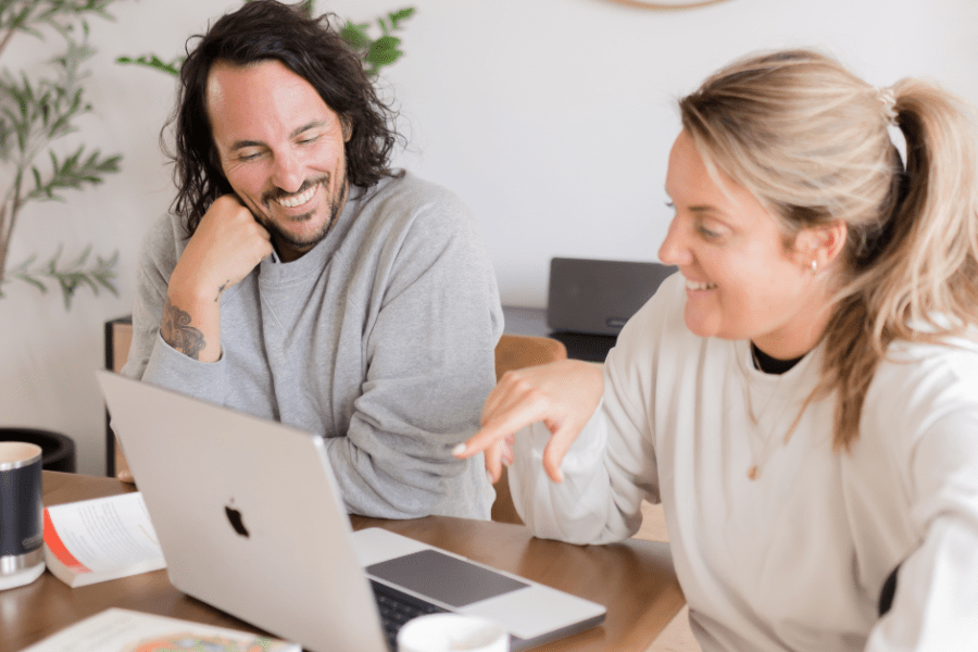 Patrick Franco and Kate Lombardo of YogaRenew looking at a laptop with YogaRenew's 200 hour online yoga teacher training pulled up