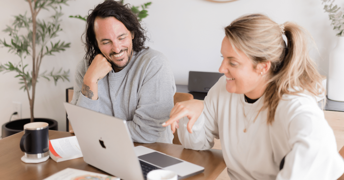 Patrick Franco and Kate Lombardo of YogaRenew looking at a laptop with YogaRenew's 200 hour online yoga teacher training pulled up