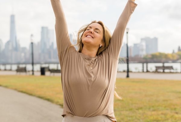 Kate Lombardo posing with her hands up in the air with peace signs to advocate for body awareness through yoga