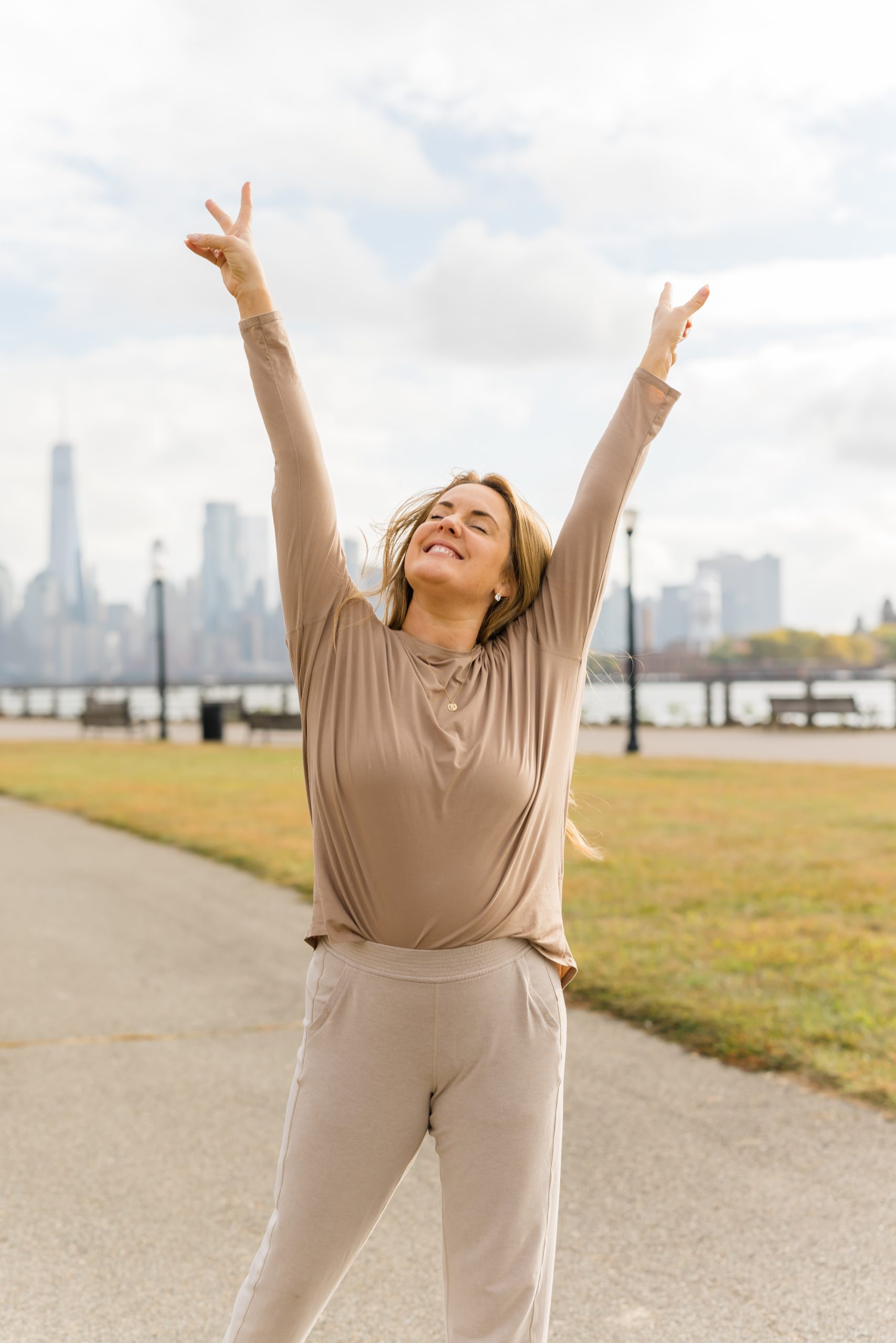 Kate Lombardo posing with her hands up in the air with peace signs to advocate for body awareness through yoga