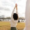 Mindful morning yoga flow image of a yogi in Urdhva Hastasana with their back towards us, overlooking a Hoboken park