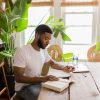 Jordan Matthews of YogaRenew sitting at a wood table, going over his mantras written in his journal