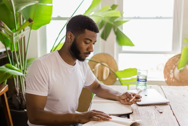 Jordan Matthews of YogaRenew sitting at a wood table, going over his mantras written in his journal